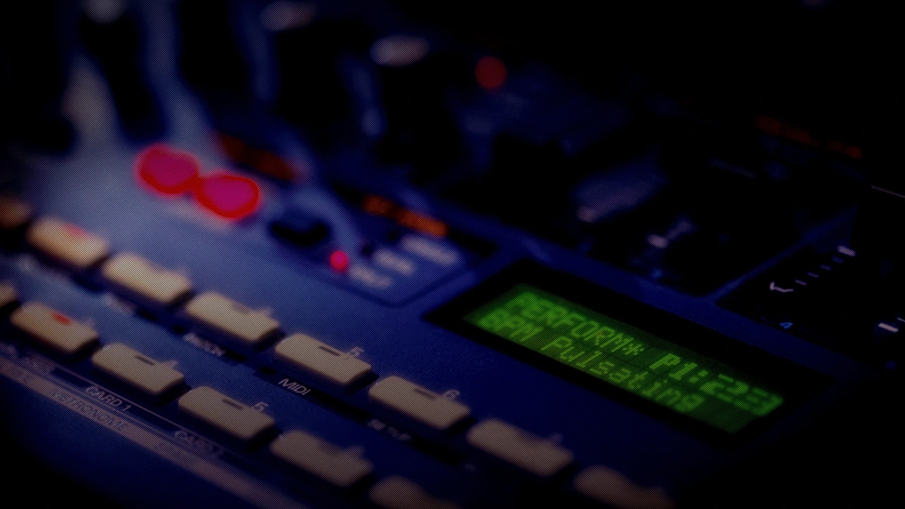 Roland JP‑8080 synthesizer front panel with illuminated LCD screen and control buttons in a dark studio setting.
